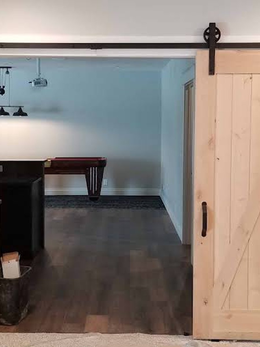 Custom light-wood barn doors on a black sliding track between two rooms.